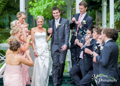 Bridal party blowing bubbles as the bride and groom walk through them