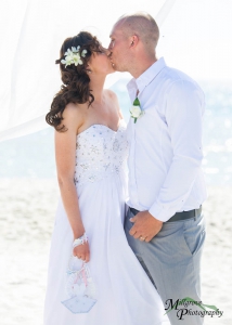 Bride and groom kissing at the beach wedding