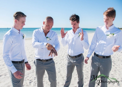 Groomsmen look in shock at groom's wedding ring