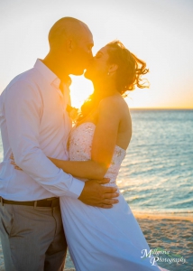 Bride and groom kissing with the sunset behind them