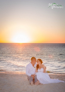 Bride and groom sitting on the beach with the sunset