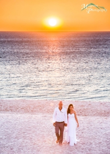 Bride and groom walking on the beach at sunset