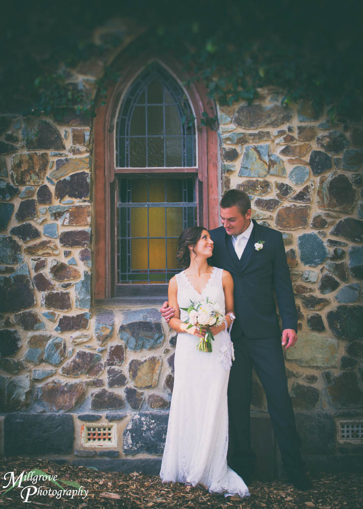 A bride and groom by a stone wall at Inglewood Estate