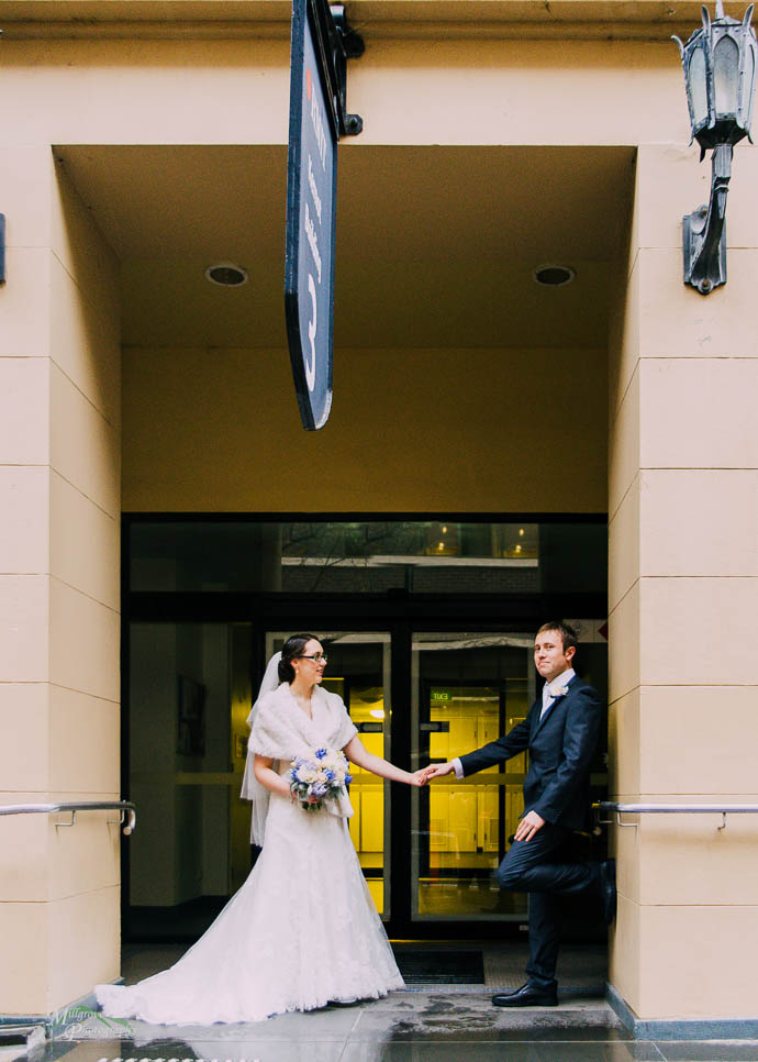 Bride and groom holding hands in building entrance