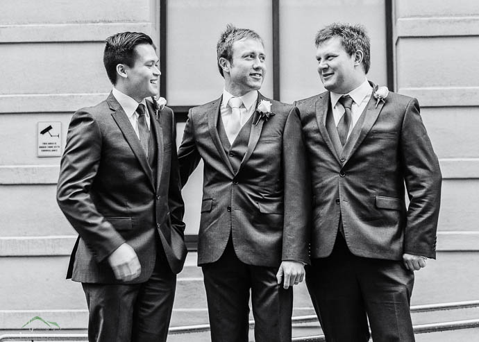 Groom and groomsmen laughing, black and white