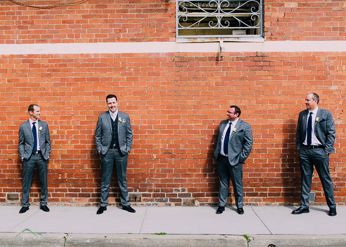 Groomsmen by a brick wall