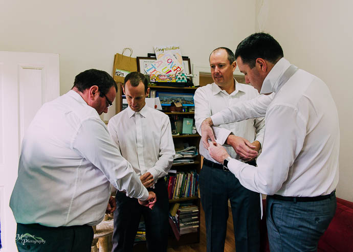 Groom and groomsmen doing cufflinks