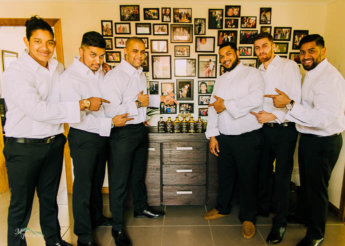 Groom and groomsmen pointing at bottles