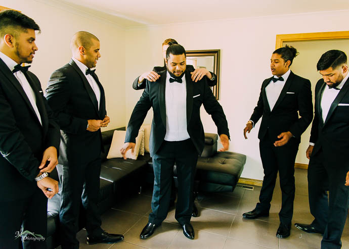 Best man helping groom pu ton his jacket