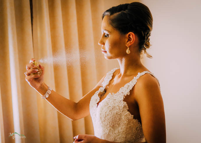 Bride spraying perfume out of bottle, pre-wedding