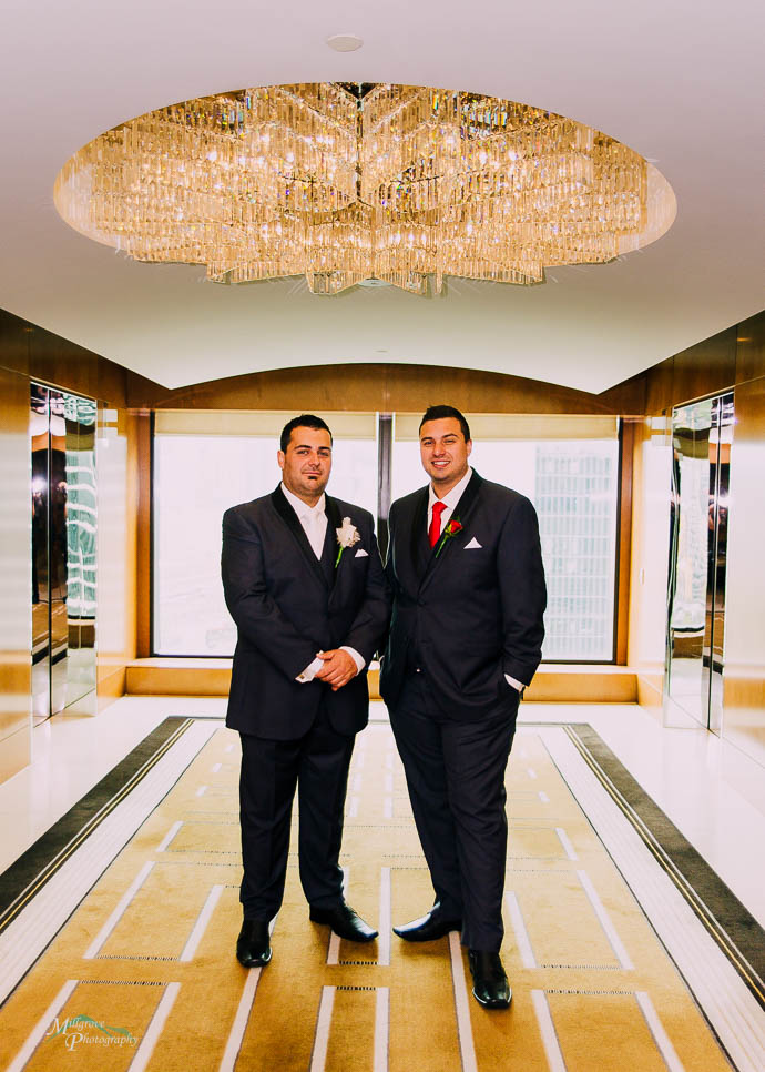 Groom and groomsman under a chandelier