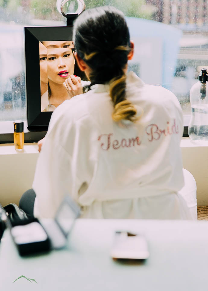 Bridesmaid doing her makeup in a little square mirror