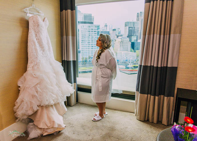 Bride looking up at her wedding dress with the city in the backg