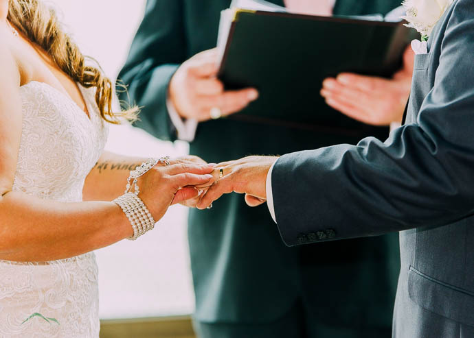 Bride putting wedding ring on groom's finger