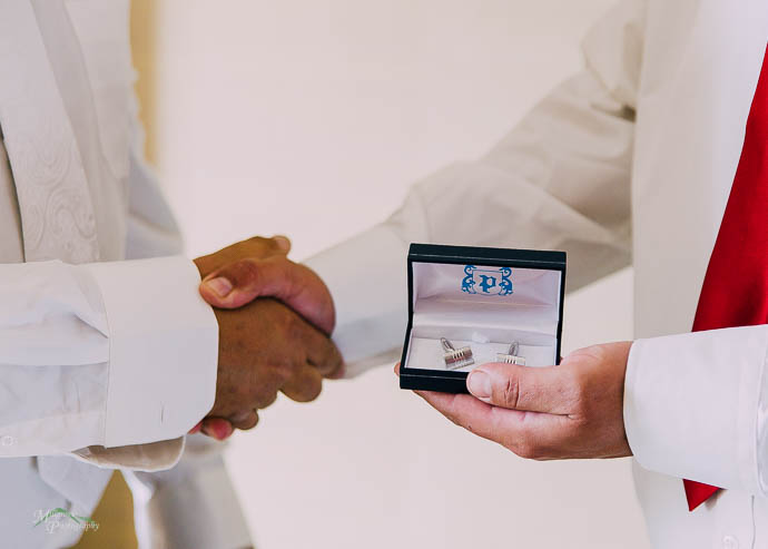 Groom handing cufflinks to a groomsman