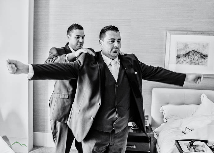 Groomsman helping groom with his tie