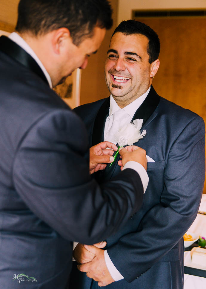 Groomsman helping groom with his tie