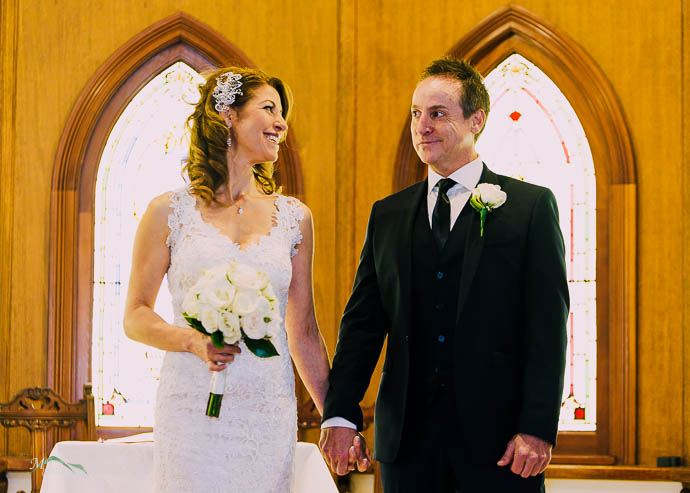 Bride and groom in a chapel wedding with stained glass windows