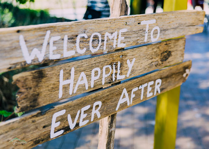 Wooden sign saying "Welcome to Happily Ever After" at a wedding