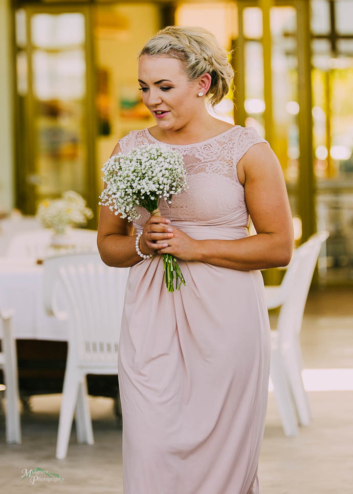 Bridesmaid in pink dress walking down the aisle