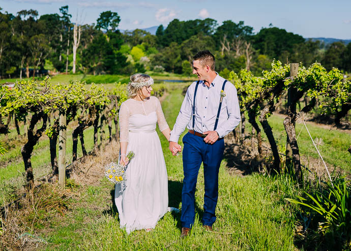 Bride and groom walking amongst the vines at a vineyard wedding