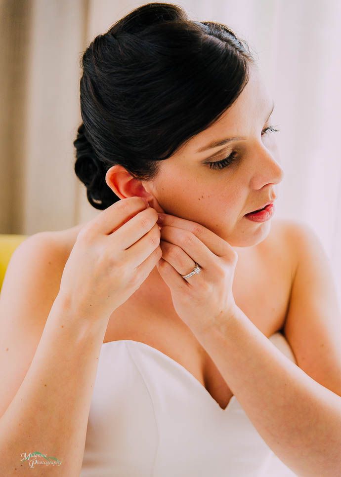 Bride putting on her earrings in the bridal suite at Lake House,