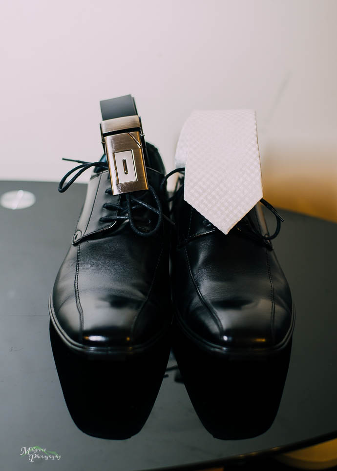 Groom’s shoes with his tie and belt placed on top