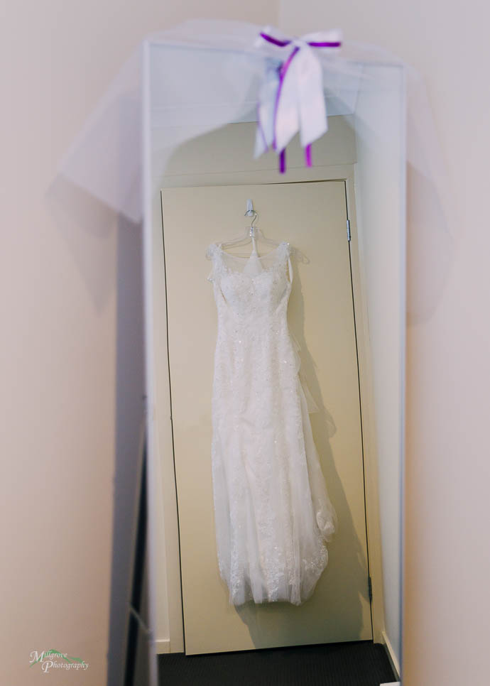 Bride’s dress hanging against a door