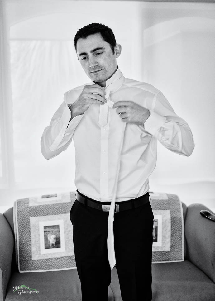 Groom putting on his tie