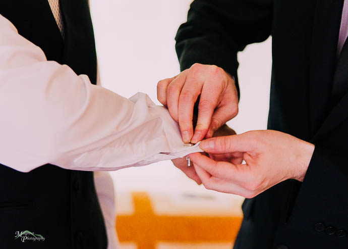 Groom getting help from Groomsmen to put on his cufflinks