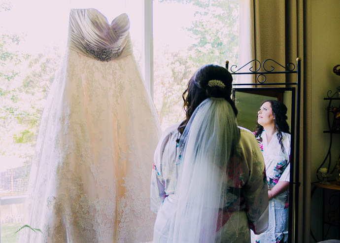 Bride looking at her dress hanging in the window