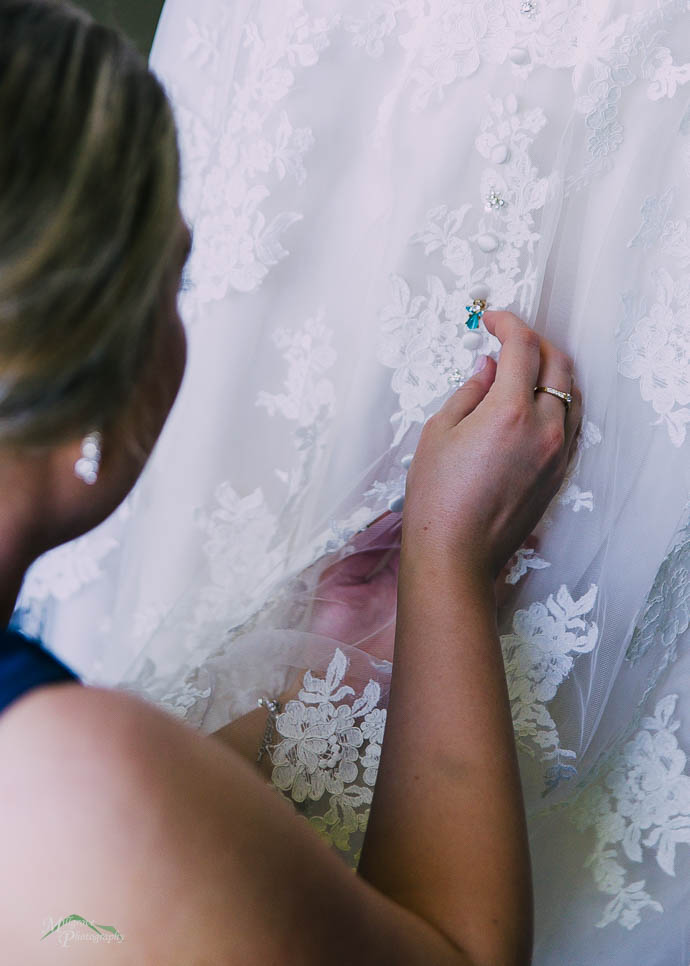 Bridesmaid pinning something onto Bride’s dress