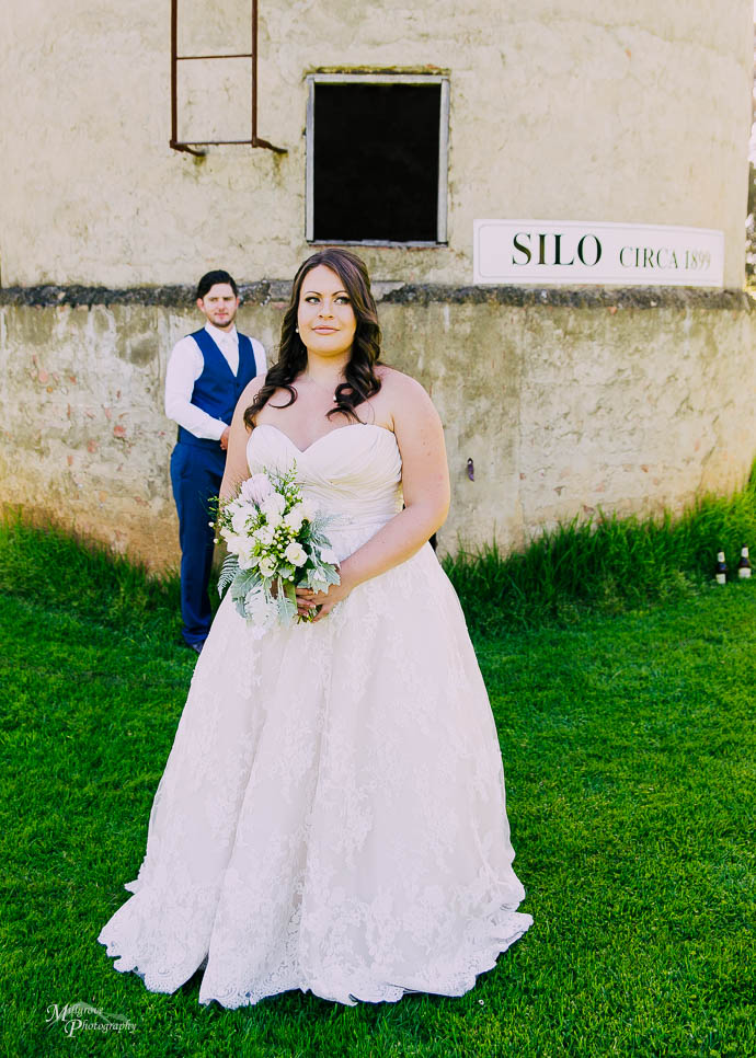 Bride smiling with Groom in the background
