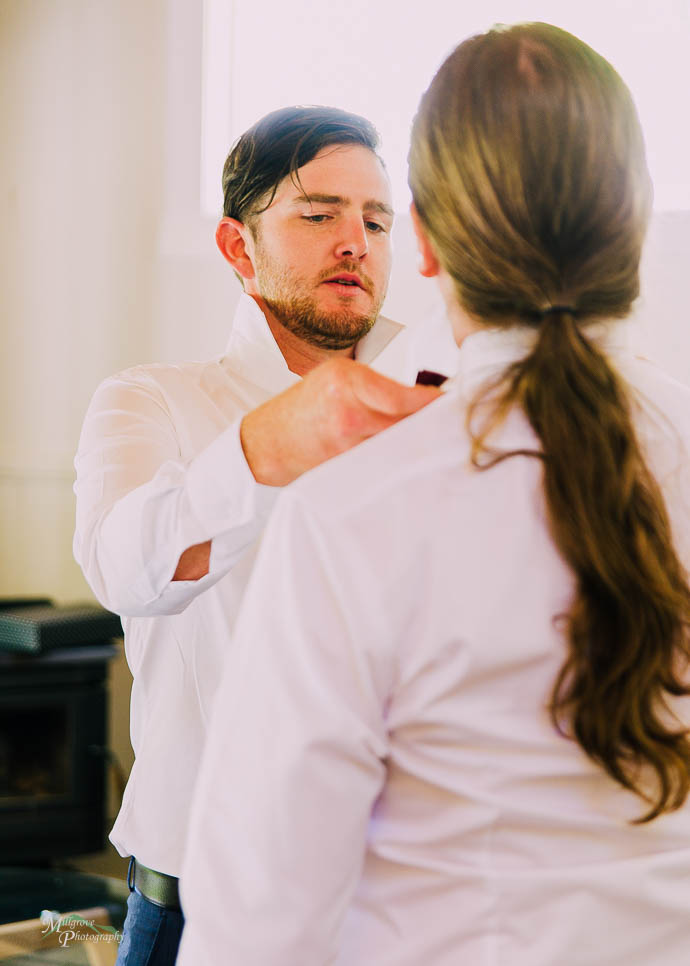 Groom adjusting Groomsman’s tie