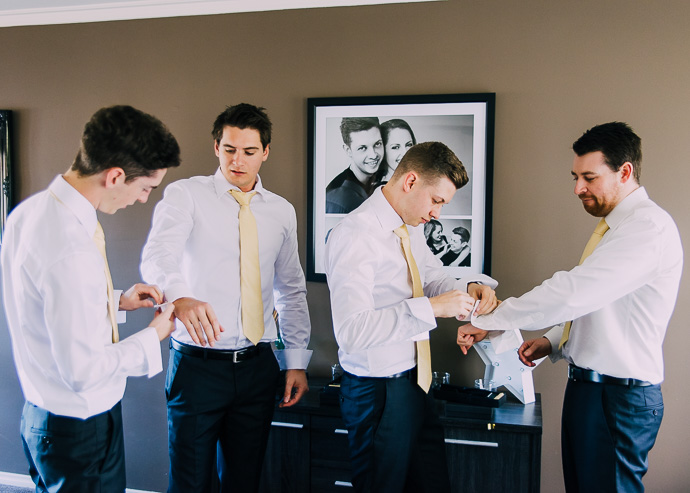 Groomsmen helping put jacket on