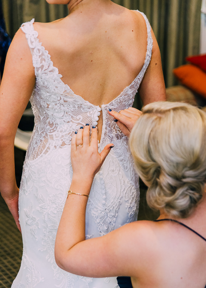 Bridemaids doing up bride's dress ribbon