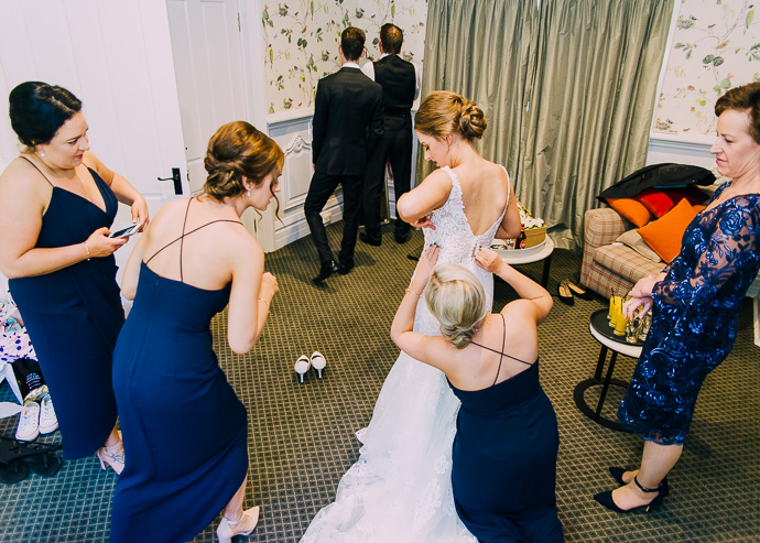 Bridesmaids helping do up dress