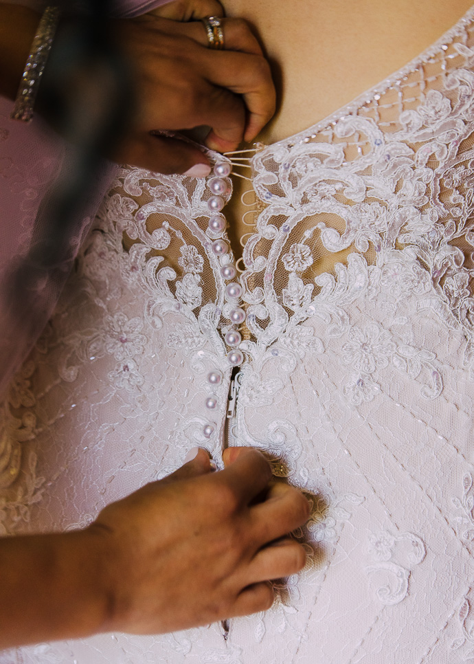 Hands doing up a wedding dress