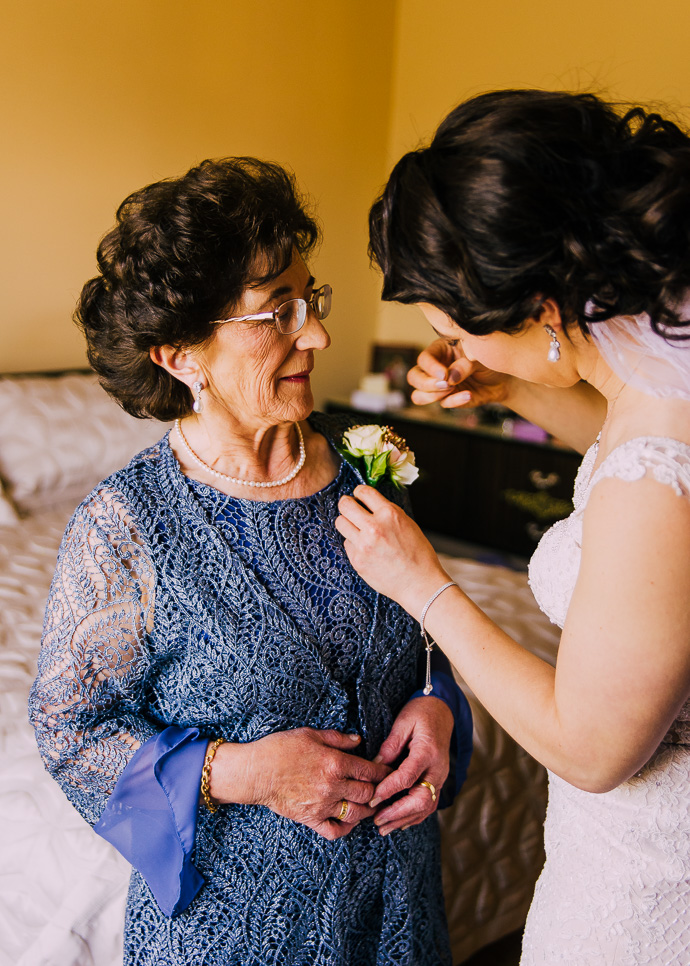 A bride pinning a flowers on her mother's dress