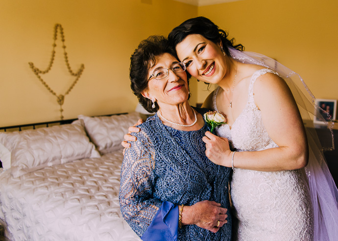 A bride pinning a flowers on her mother's dress