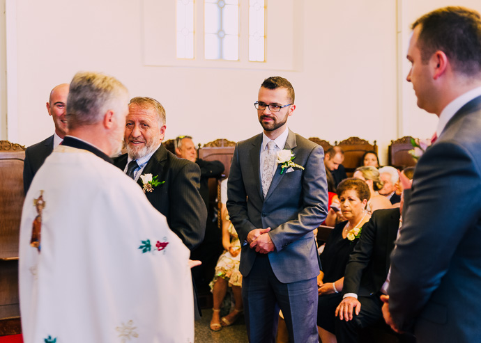 A groom standing with a priest
