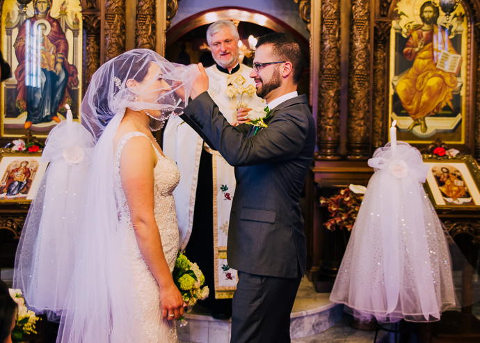 A groom lifting the bride's veil