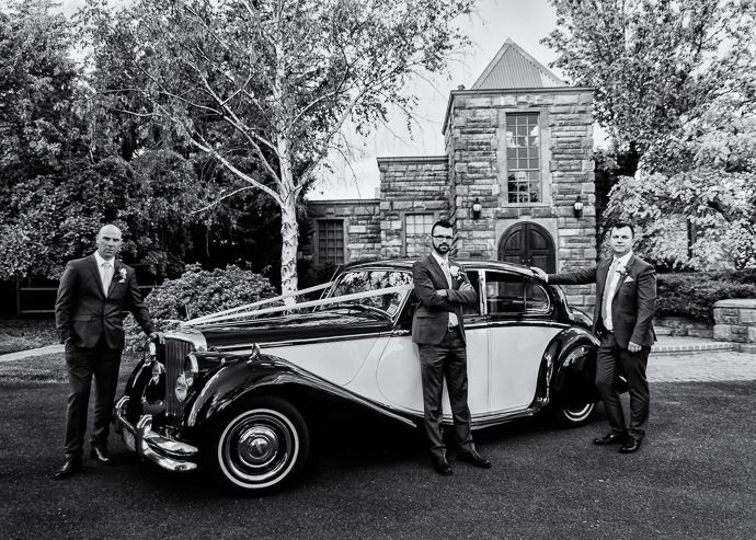 A groom and groomsmen with a wedding car outside Witchmount Estate