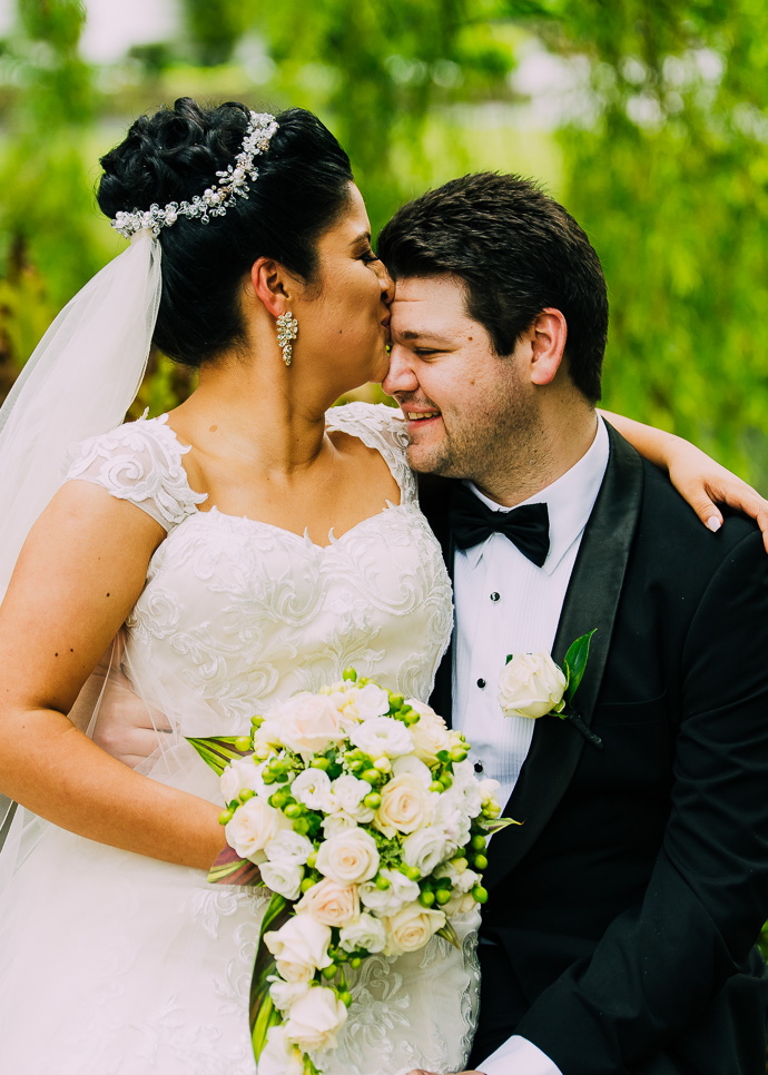 A bride kissing the groom on the forehead