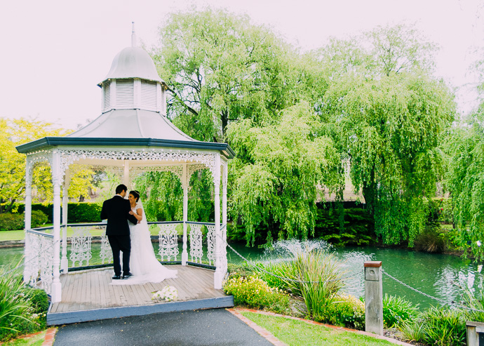 A bride and groom cuddling in a gazebo