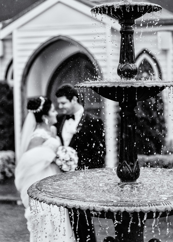 A bride a groom walking by a fountain