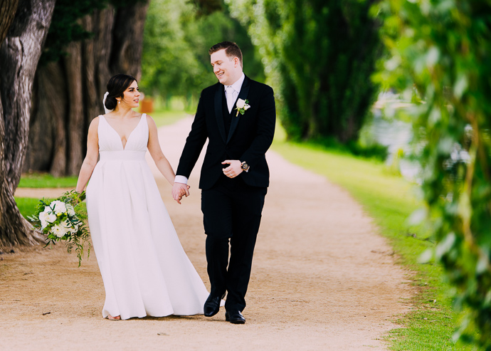 A bride and groom walking next to Albert Park LAke, near Carousel in St Kilda