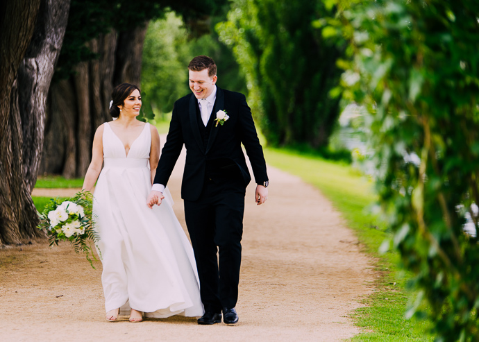 A bride and groom walking next to Albert Park LAke, near Carousel in St Kilda